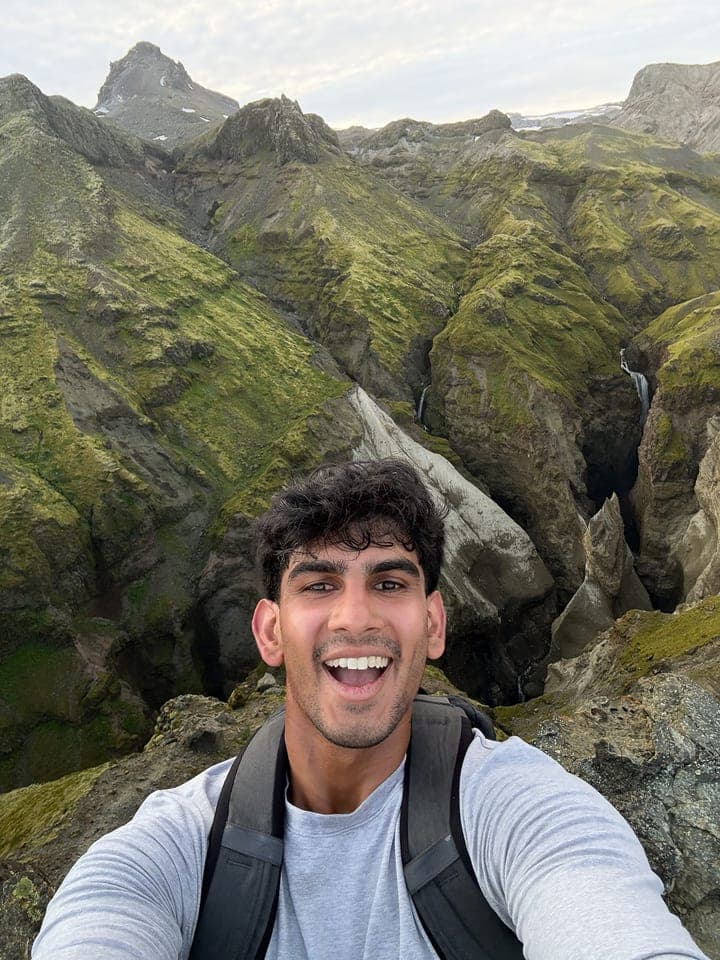 Me on a hike, with a mossy green canyon behind me